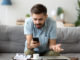 Confused man using phone sitting on couch